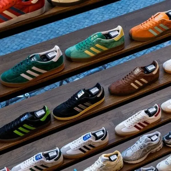 Chaussures Adidas de diverses couleurs alignées sur des étagères en bois.