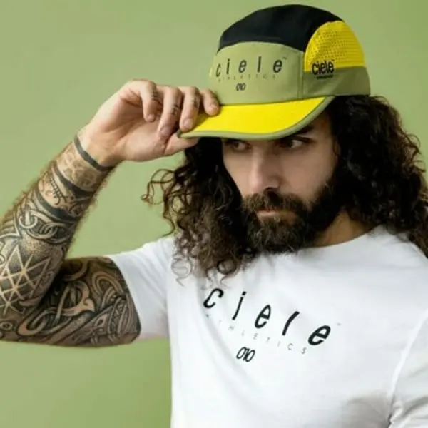Homme avec un tatouage, portant une casquette et un t-shirt Ciele Athletics, regarde vers la gauche