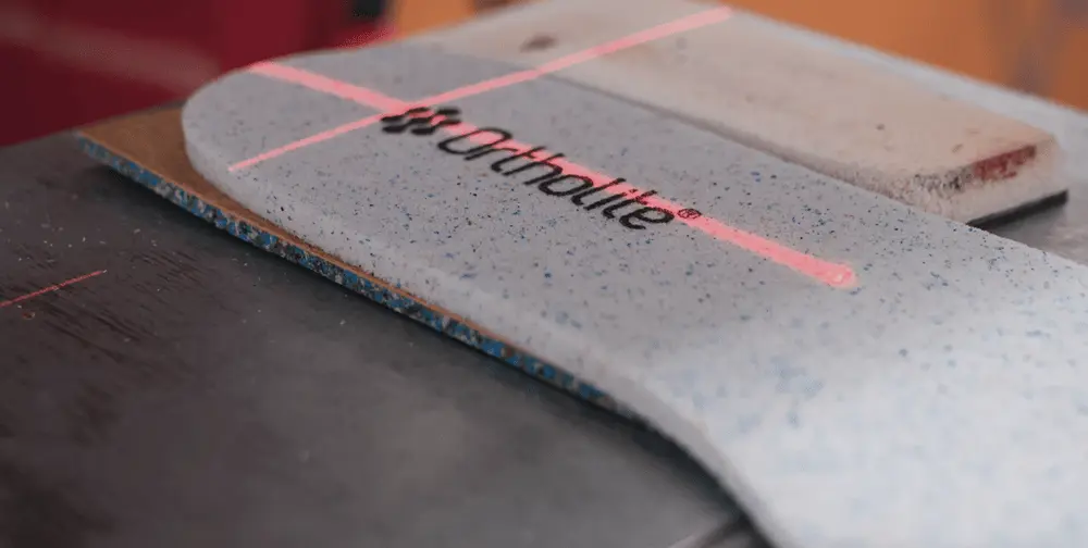 Semelle intérieure OrthoLite avec logo visible sous un éclairage rougeoyant, représentant l'innovation en confort.