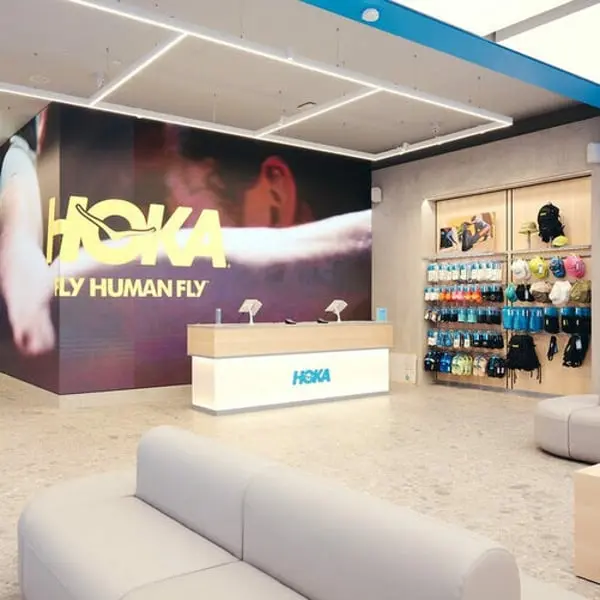 Boutique Hoka avec affichage mural et présentoirs de produits, illustrant le succès de Deckers Brands