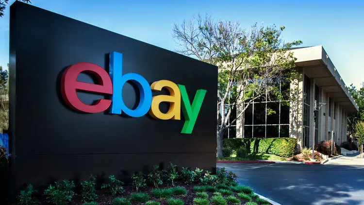 Le siège social d'eBay avec le logo coloré en façade et une allée arborée adjacente