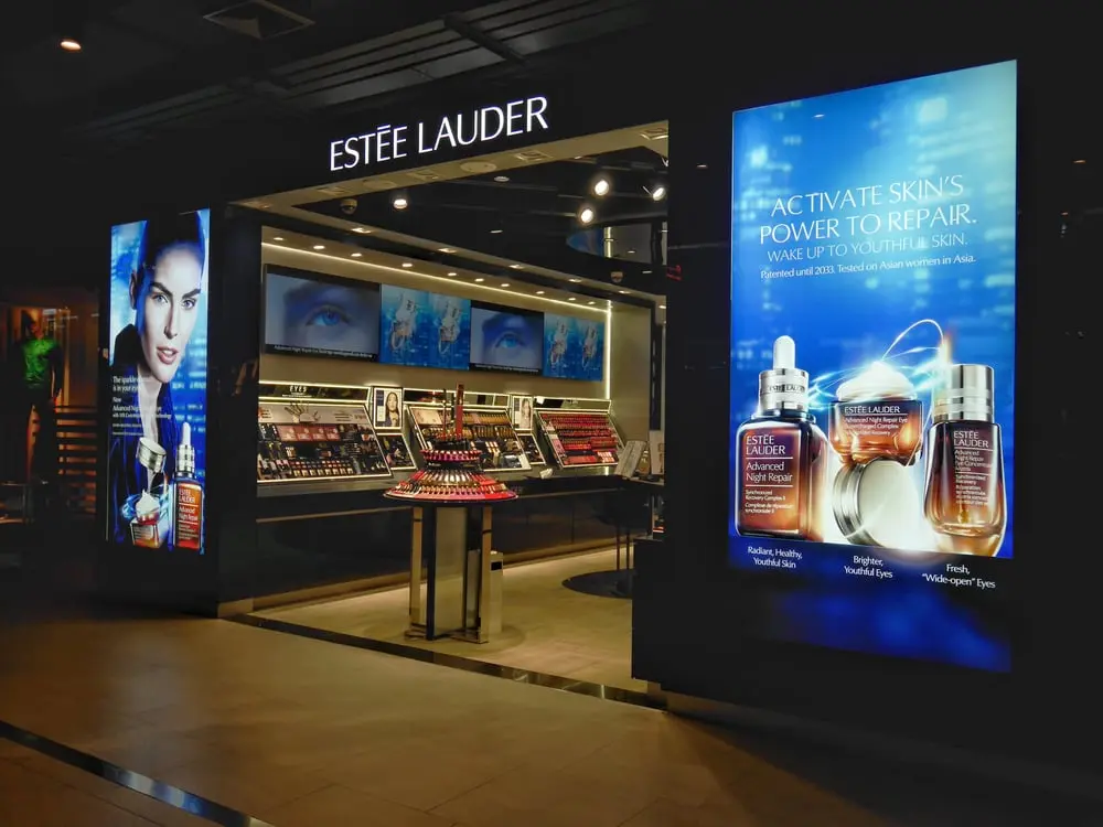 Boutique Estée Lauder avec affiches promotionnelles et présentoirs de produits cosmétiques lumineux