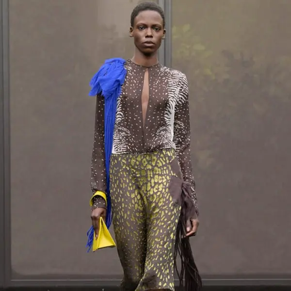 Modèle défilant en tenue Ferragamo avec motifs animaliers, accessoires bleu et jaune, pendant la présentation d'une collection