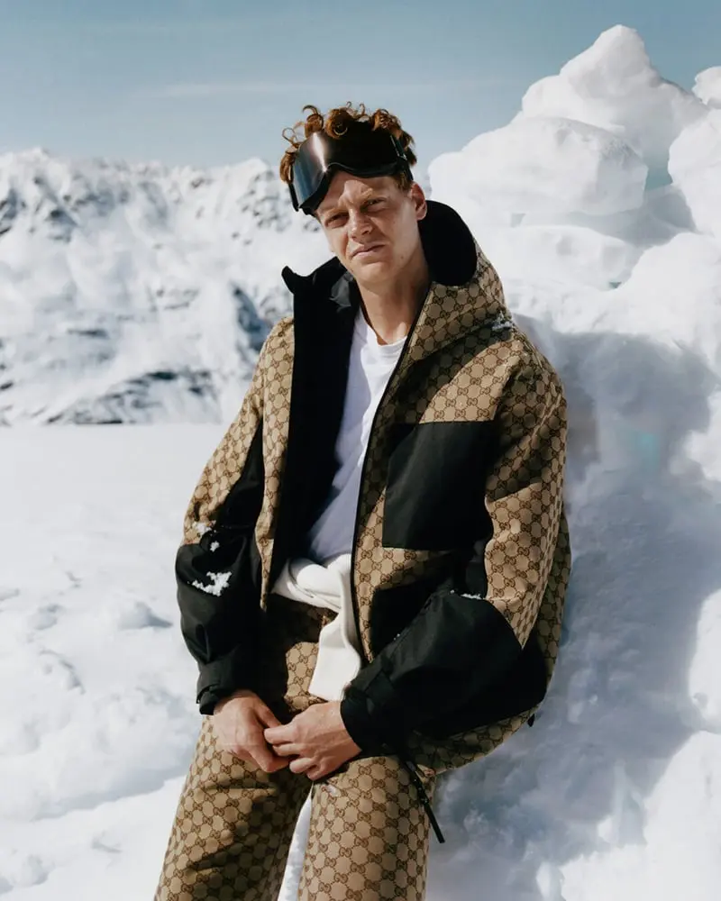 Jannik Sinner porte une tenue de ski Gucci devant un paysage enneigé, illustrant la collection Altitude