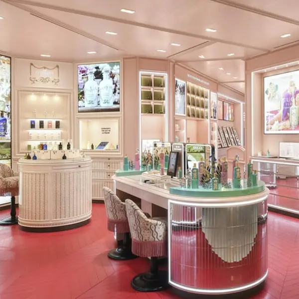 Intérieur d'une boutique Gucci avec des présentoirs de parfums élégants et un décor raffiné dans des tons pastels.