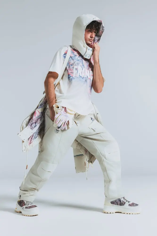 Personne portant des vêtements Le Coq Sportif pour les Jeux Olympiques d'hiver 2026, habillé en tenue sportive blanche