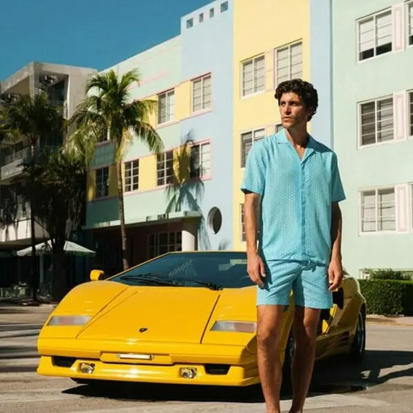 Homme en tenue estivale Orlebar Brown devant une Lamborghini jaune à Miami Beach