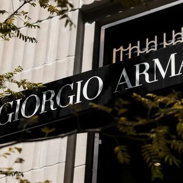 Enseigne noire Giorgio Armani avec lettres blanches sur bâtiment, branches d'arbre en premier plan