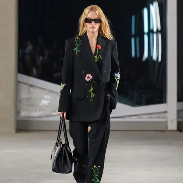 Une mannequin défile lors de la Riyadh Fashion Week 2025, portant un ensemble noir Stella McCartney orné de fleurs.