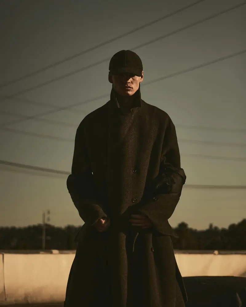 Homme portant un long manteau Auter dans un décor urbain au crépuscule