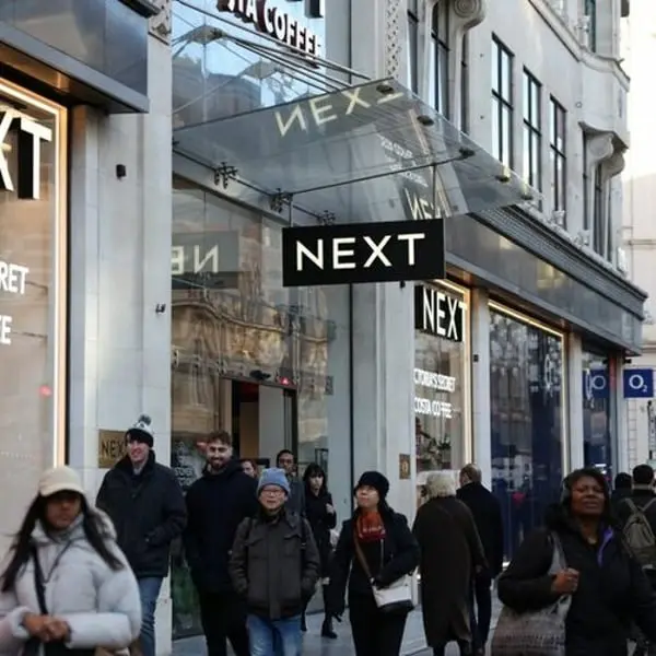 Devanture du magasin Next au Royaume-Uni avec des clients marchant dans la rue animée.