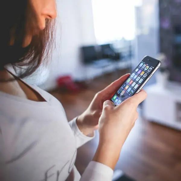 Une femme utilise un smartphone dans un intérieur moderne, illustrant les ventes en ligne de Noël.