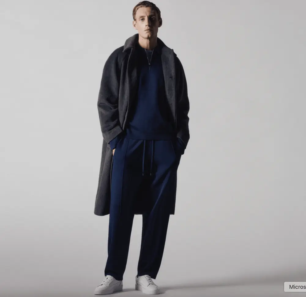 Homme en tenue décontractée bleue et manteau long, posant dans un studio pour ASOS