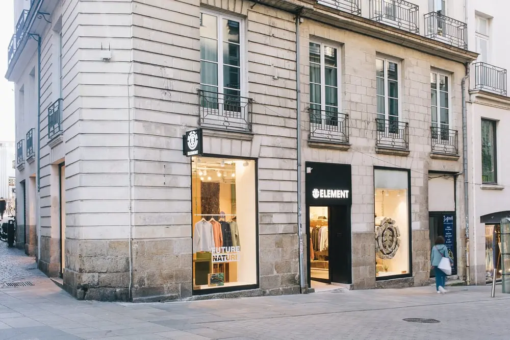 Façade d'une boutique Element dans une rue piétonne, vêtement exposé en vitrine lumineuse.