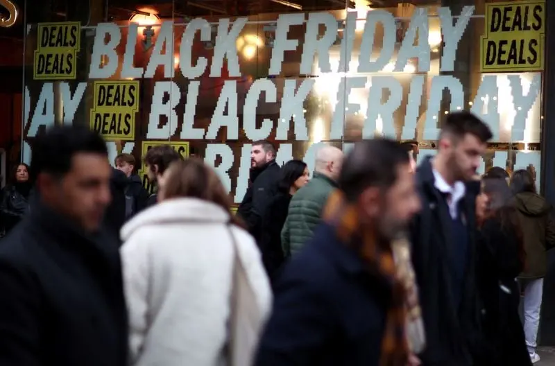 Foule de clients devant une vitrine de magasin avec des affiches Black Friday et des pancartes Deals à Londres