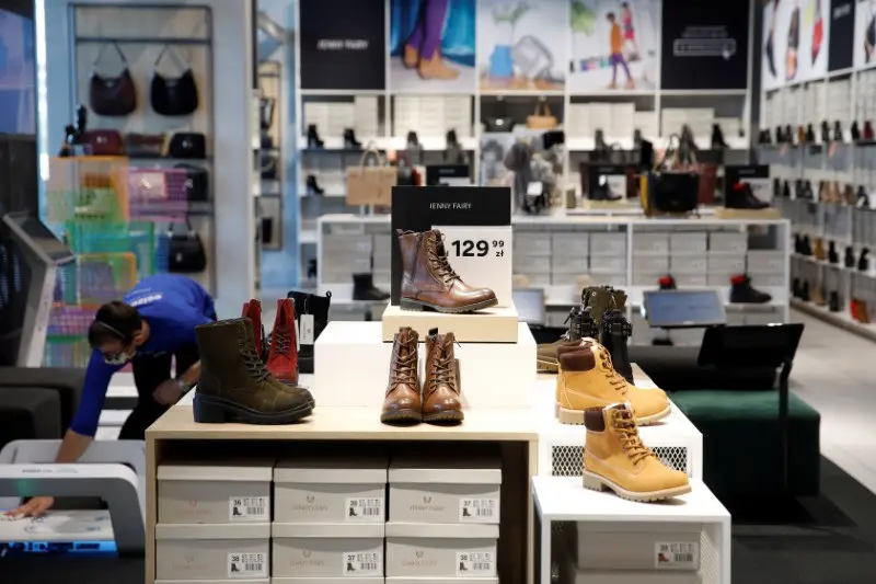 Des bottes Lenny Fairy exposées sur un présentoir dans un magasin, avec des affichages de prix en arrière-plan