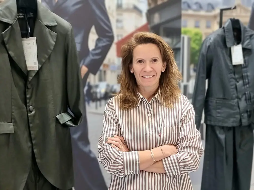 Fatma Korkmaz de la marque Isko pose devant des tenues en denim dans un magasin moderne
