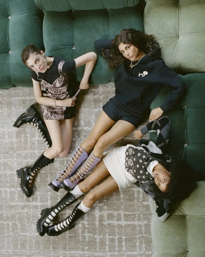 Trois femmes allongées sur un canapé vert montrent des bottes Kiki, symboles de la collaboration Dr Martens et Marc Jacobs.