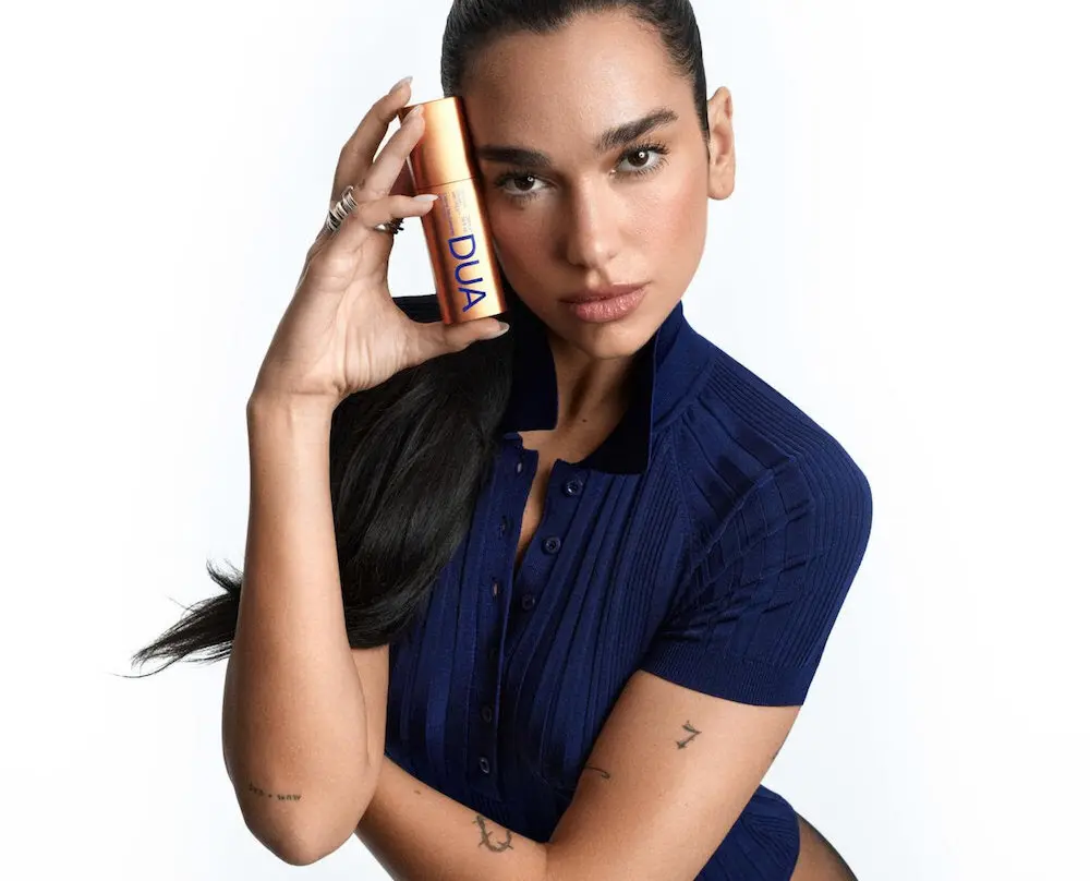 Femme tenant un flacon de soin visage de la gamme Dua Lipa en collaboration avec Augustinus Bader
