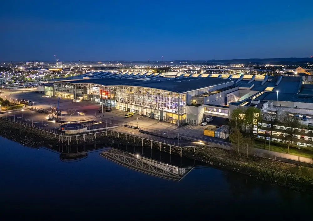Vue nocturne du centre commercial Braehead de Glasgow illuminé, avec reflet sur l'eau, acquis par Frasers Group