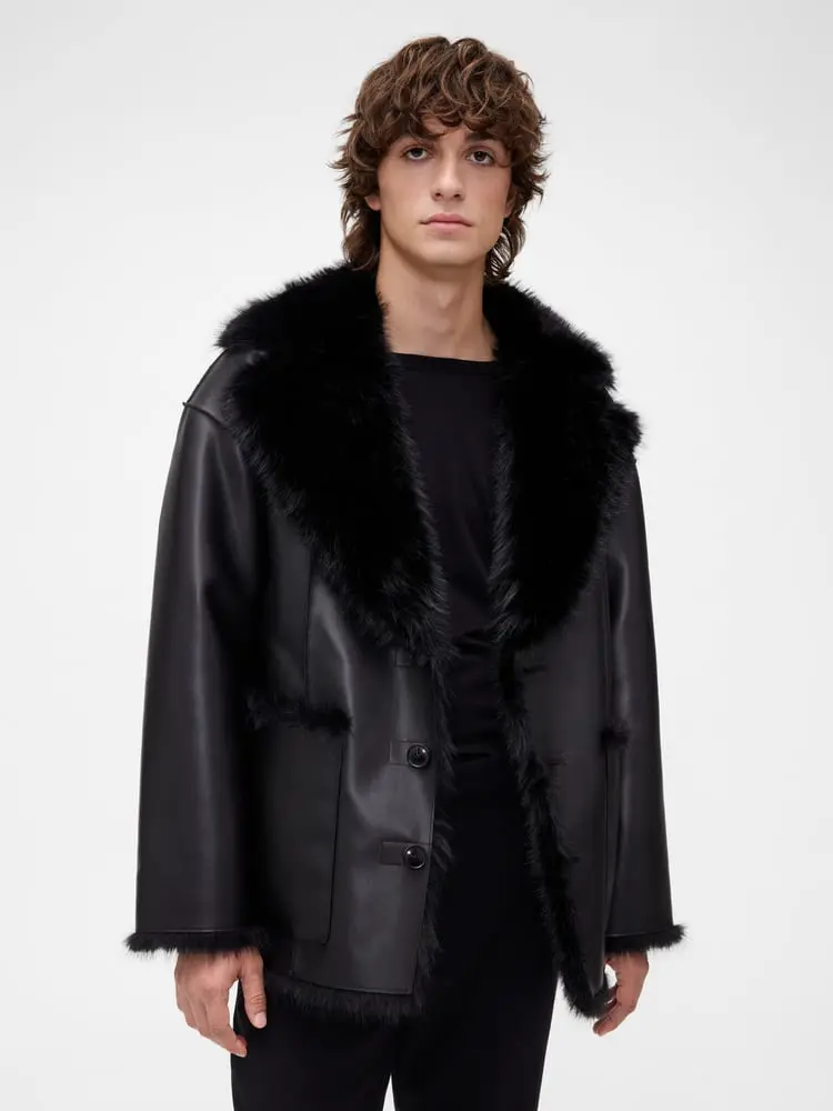 Un mannequin porte un manteau noir en cuir avec col en fausse fourrure, partie de la collection homme GapStudio pour l’hiver 2025