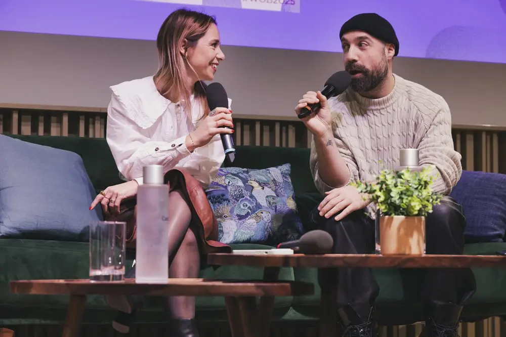 Louis-Gabriel Nouchi discutant stratégie mondiale lors d'un événement, assis avec une autre personne sur un canapé vert