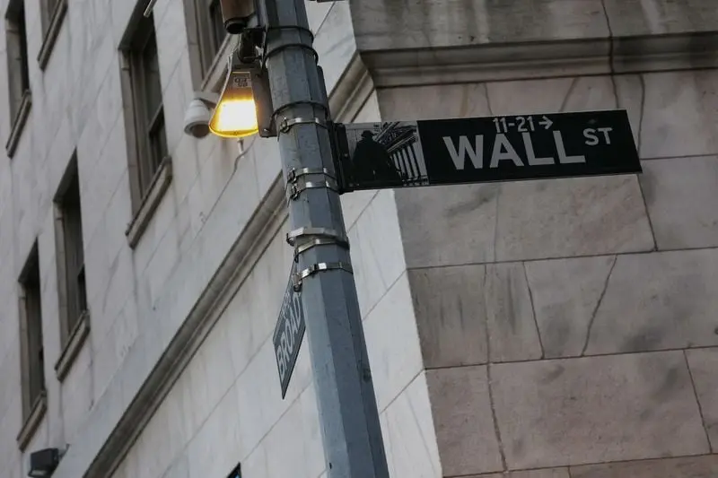 Panneau de rue indiquant Wall Street sur un lampadaire devant un bâtiment en pierre
