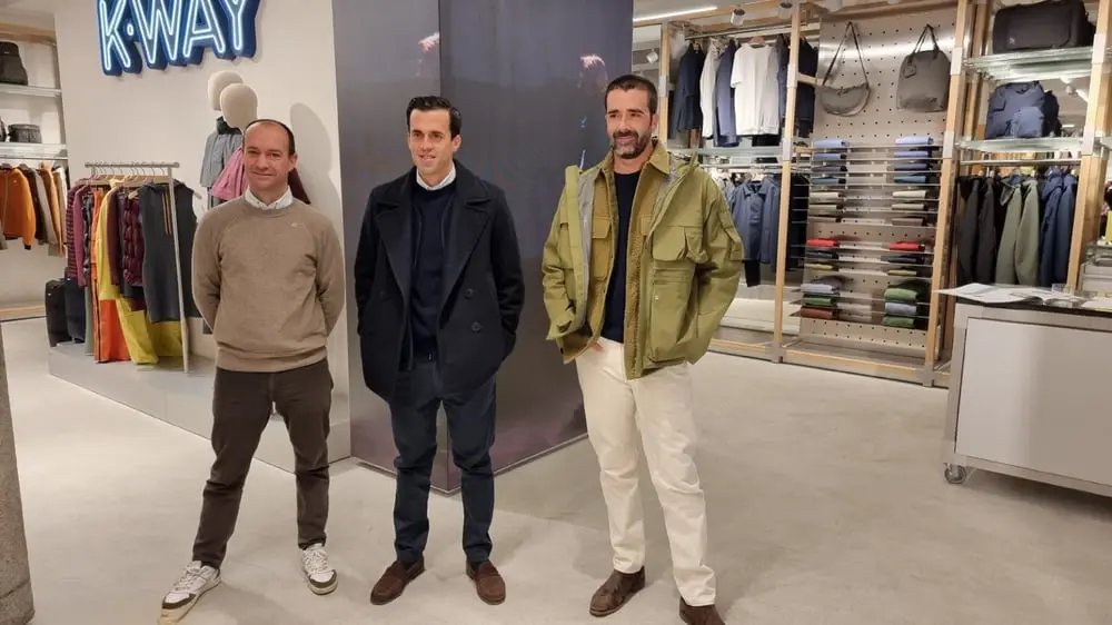 Des personnes dans un magasin K-Way à Milan, entourées de vêtements colorés et de présentoirs modernes