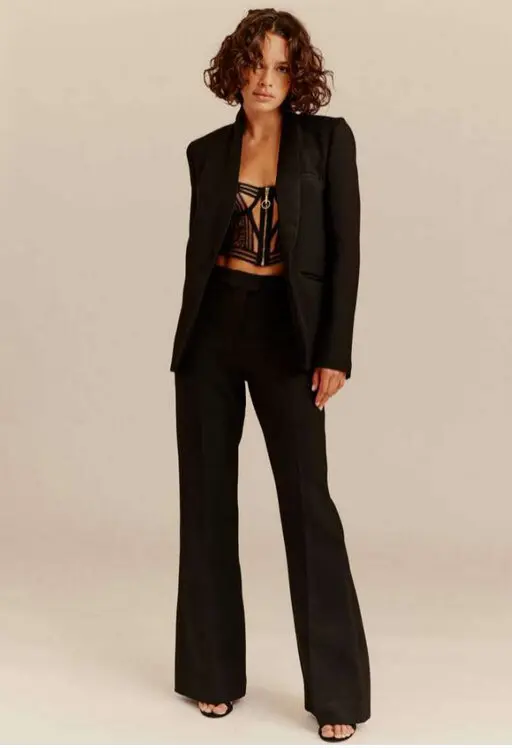 Personne posant en costume noir élégant et bustier, symbolisant l'expansion de Livy.