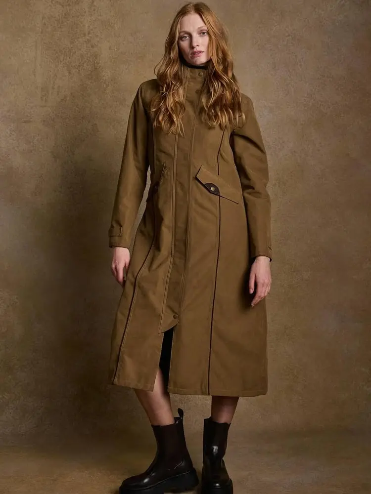 Femme portant un manteau d'hiver brun devant un fond neutre, symbole de mode annuelle