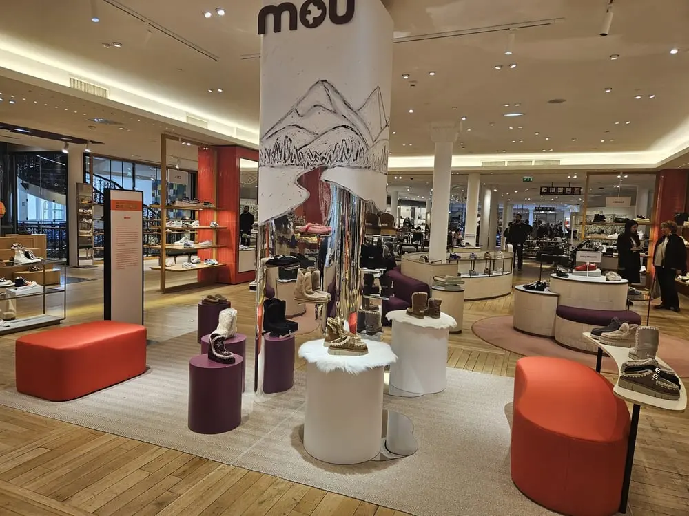 Aménagement du pop-up store de Mou au Bon Marché avec présentoirs et chaussures exposées sur des tables circulaires