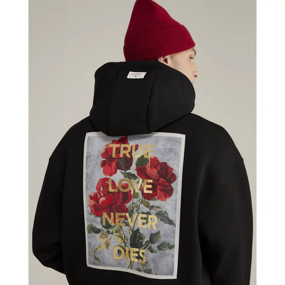 Un homme porte un sweat noir avec l’inscription "True love never dies" de la collection River Island.