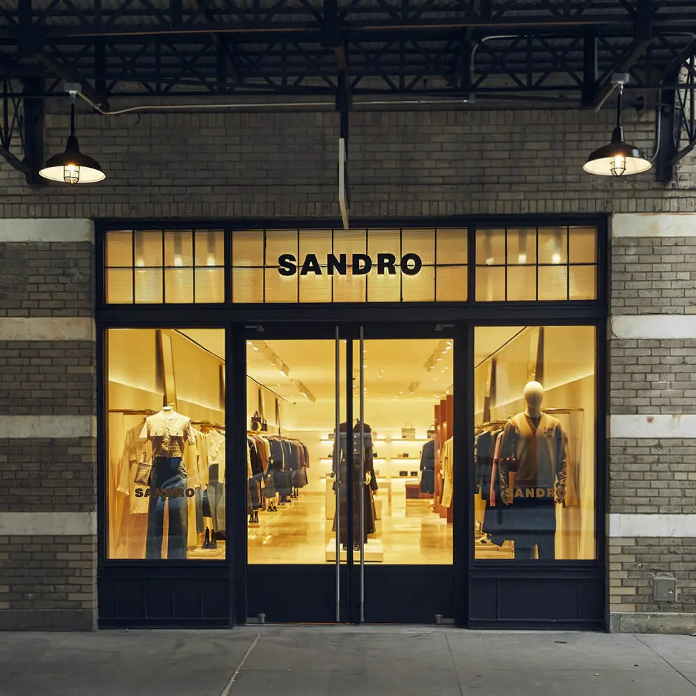Façade de la boutique Sandro avec vêtements exposés, éclairage chaleureux et enseigne visible