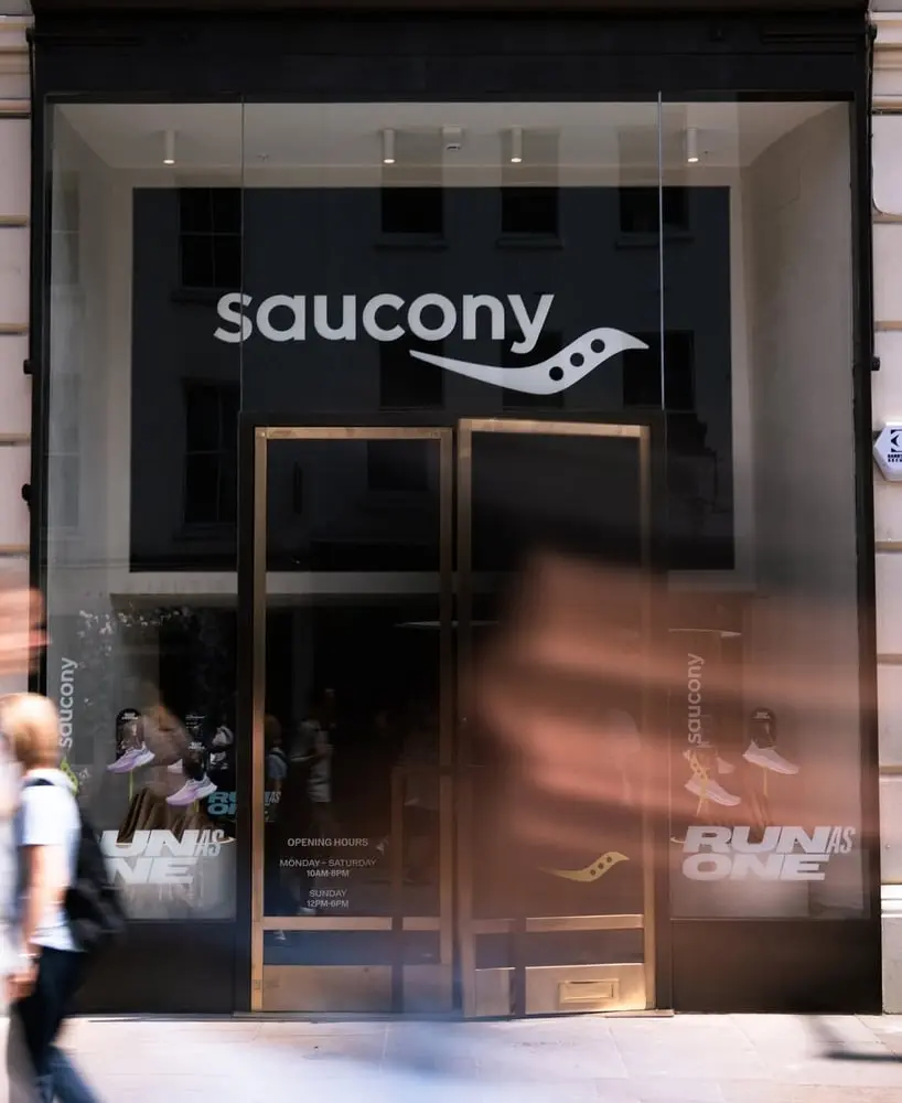 Façade du magasin Saucony avec des passants flous, représentant la croissance de Wolverine Worldwide