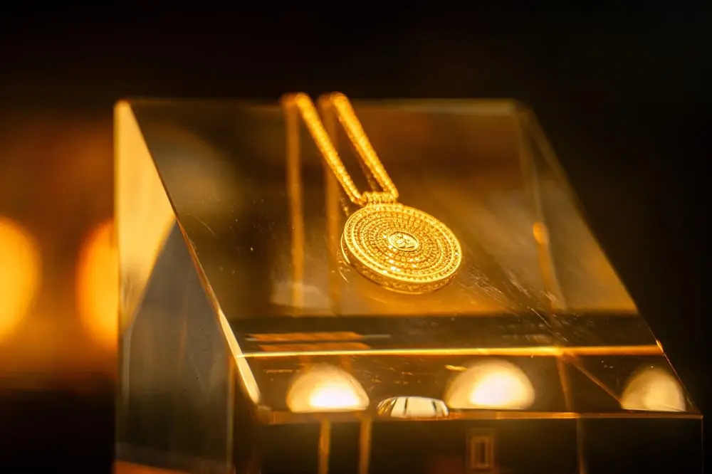 Pendentif en or sur un support illuminé, symbole de l'investissement de Kering dans les bijoux de luxe.