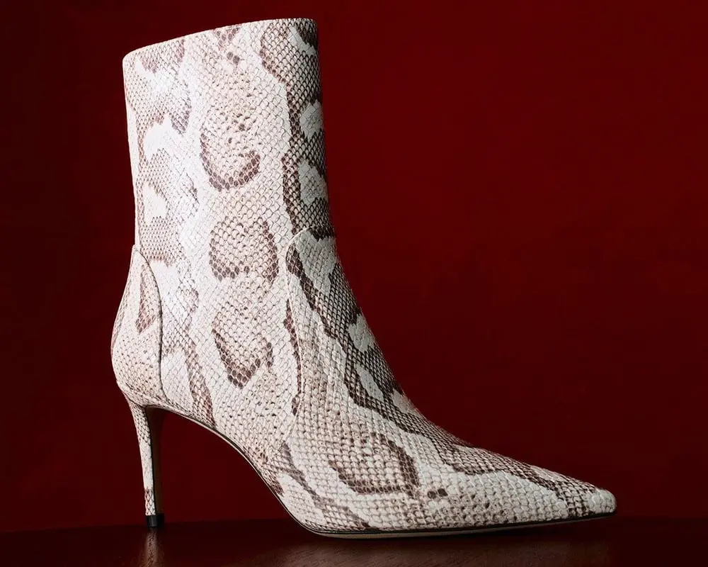 Bottine à talon motif serpent sur fond rouge, illustrant l'expansion de la marque Caleres grâce à Stuart Weitzman