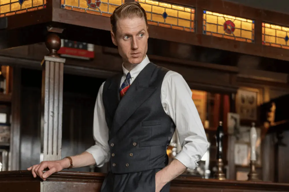 Homme en costume trois pièces sombre dans un lieu vintage, mettant en valeur la mode cathartique de Cathcart London