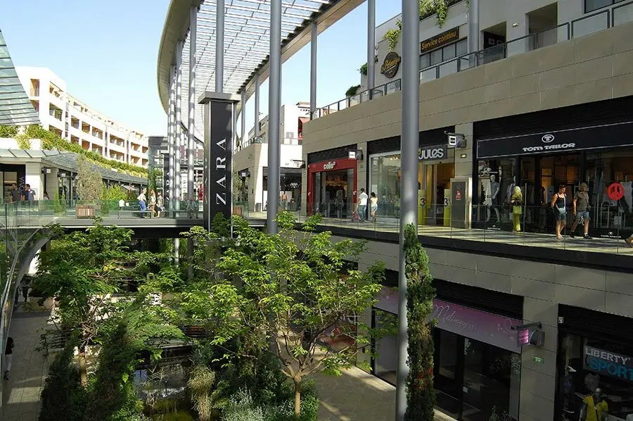 Centre commercial avec boutiques comme Zara, entouré de verdure, illustrant l'expansion internationale de Ceiba
