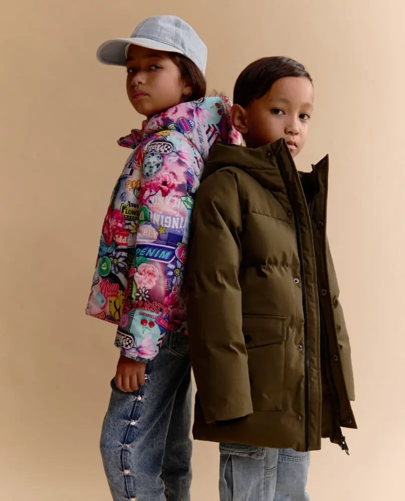 Deux enfants portant des vêtements Vingino, l'un avec une veste colorée et une casquette, l'autre en doudoune kaki