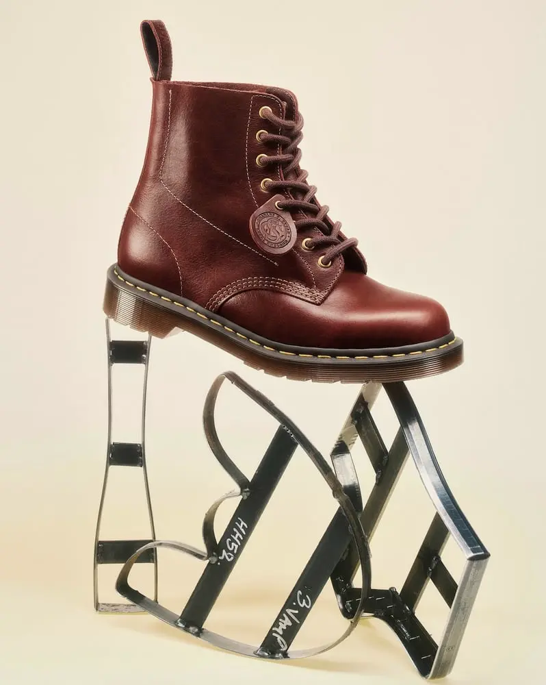 Botte Dr Martens marron posée sur une structure métallique en forme de cœur avec semelle à surpiqûres jaunes
