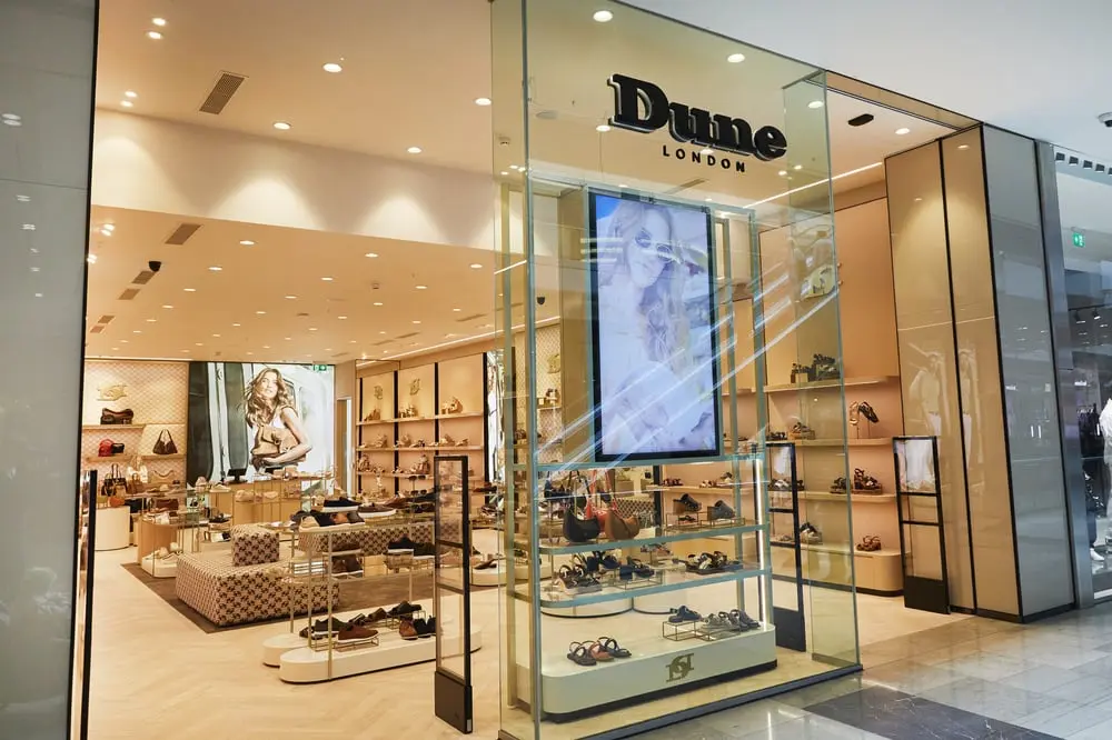 Boutique Dune London éclairée avec présentoirs de chaussures et sacs modernes dans un centre commercial élégant