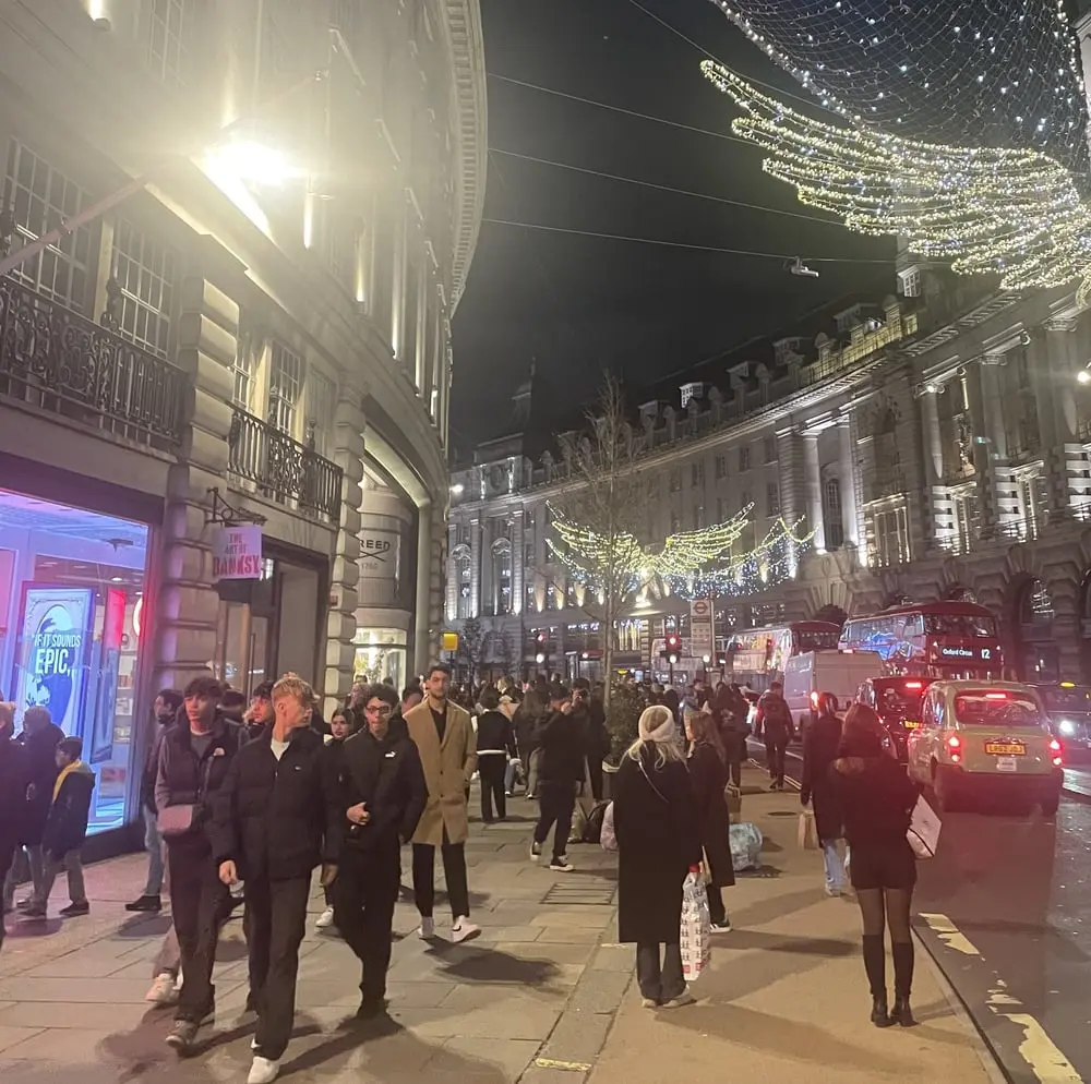 Foule nocturne sur une rue animée de Londres illuminée pour Noël, illustrant le footfall au Royaume-Uni en baisse