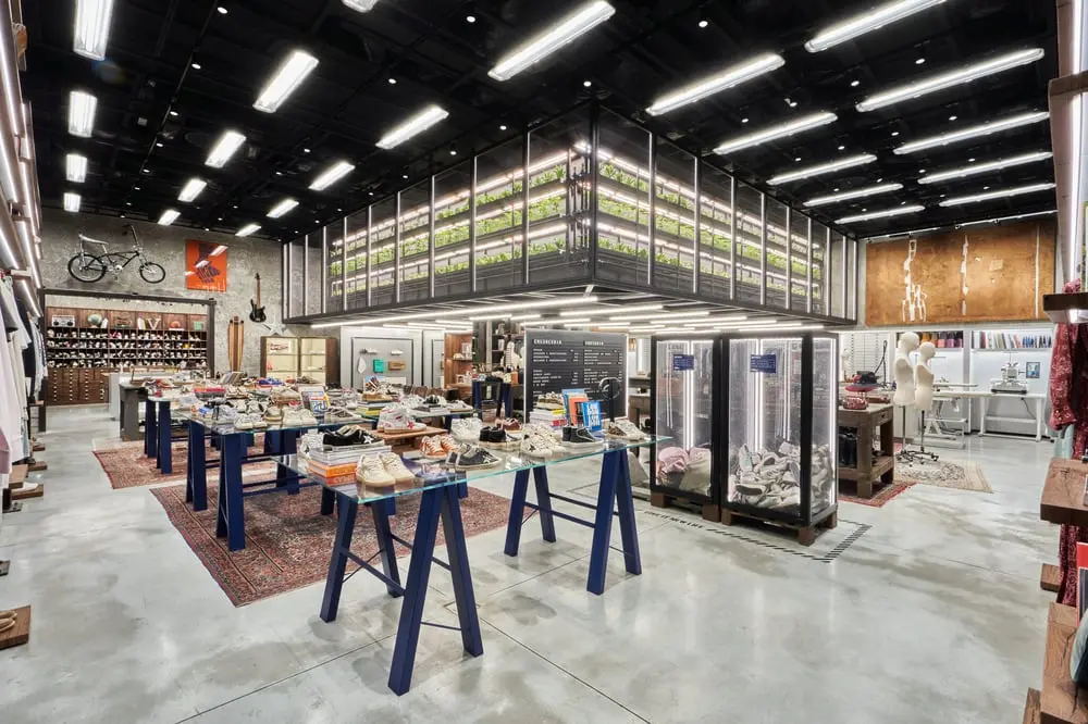 Boutique moderne de chaussures Golden Goose avec présentoirs en verre, décor industriel et éclairage lumineux.