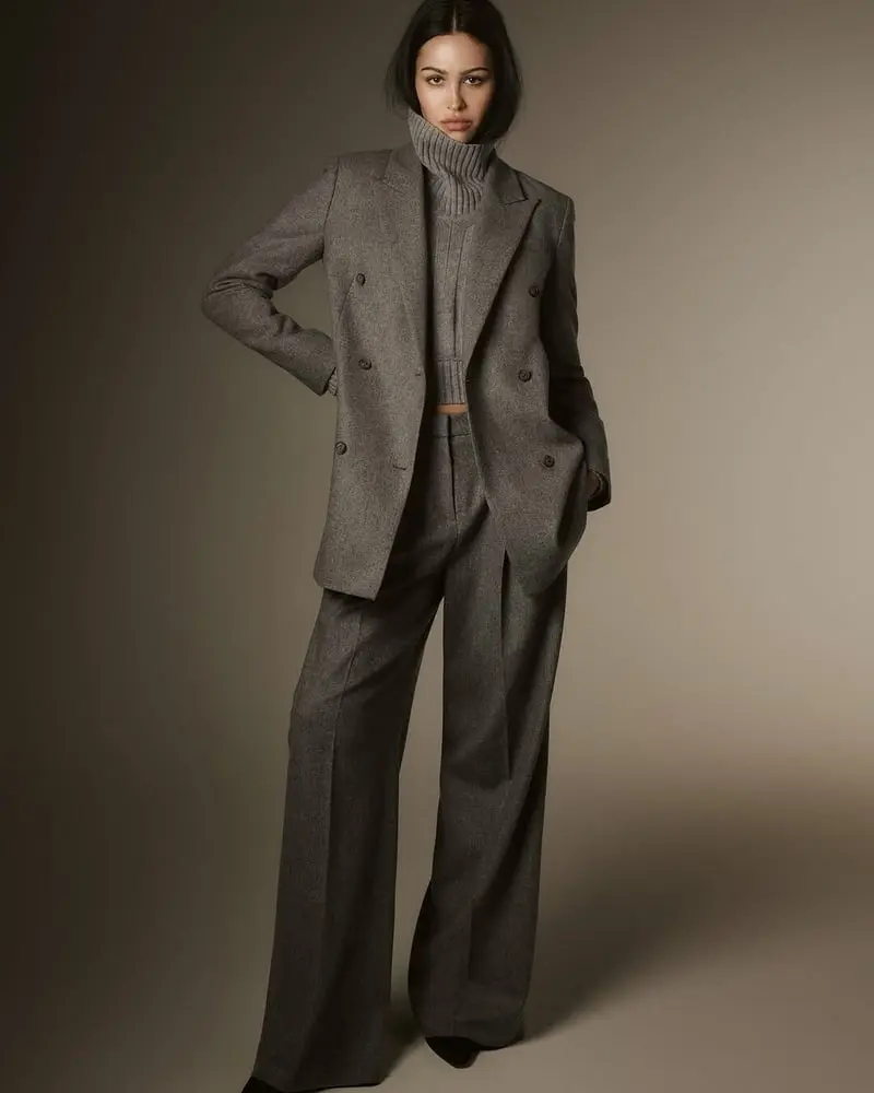 Femme portant un ensemble gris Hugo Boss dans un studio avec un fond neutre