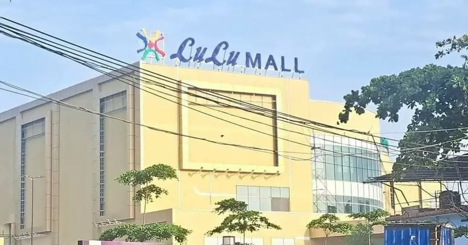 Façade moderne du LuLu Mall entourée de végétation, ciel dégagé et câbles électriques visibles