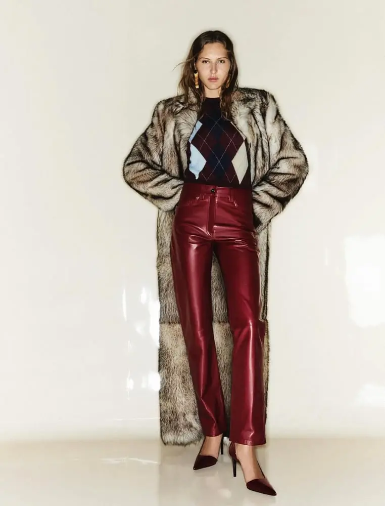 Modèle posant avec un manteau en fausse fourrure et un pantalon en cuir rouge, symbolisant l'élégance de Khaite