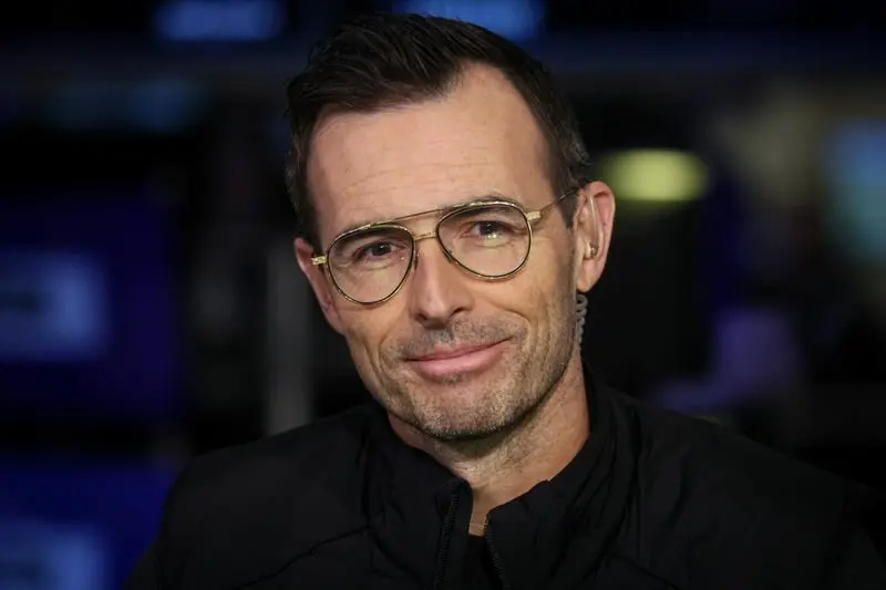 Homme portant des lunettes et une veste sombre dans un environnement de bureau, illustrant le départ du CEO de Lululemon