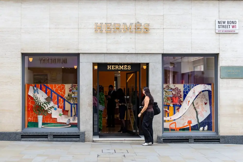 Façade d'une boutique Hermès avec une vitrine colorée et des passants à l'entrée sur New Bond Street