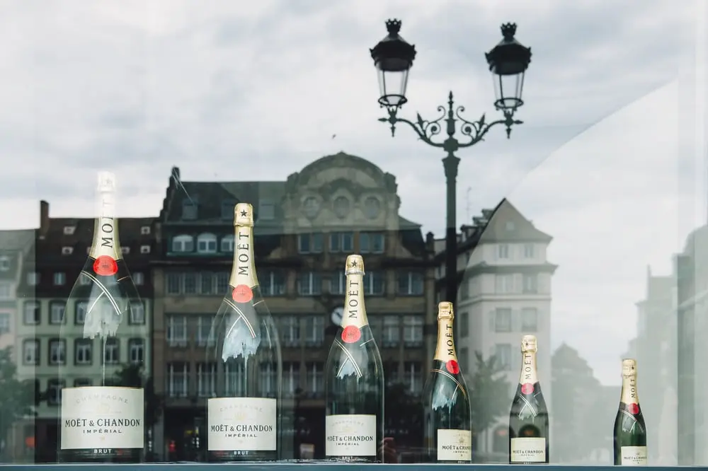 Bouteilles de Champagne Moët & Chandon alignées devant une façade urbaine, devanture de magasin LVMH visible