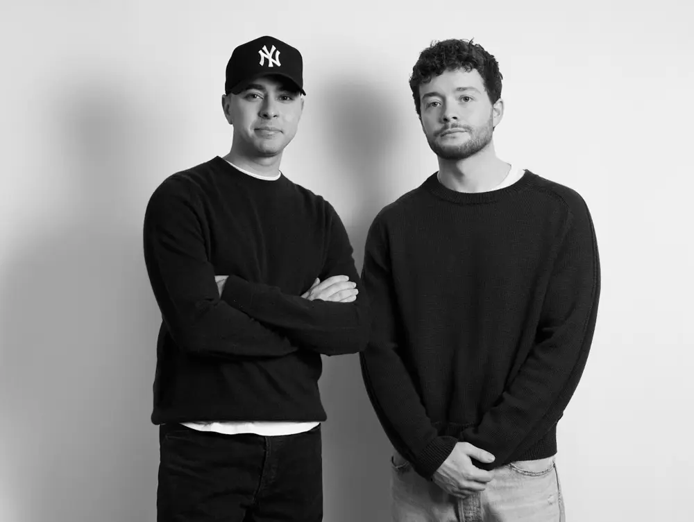 Deux hommes posent dans un studio vêtus de pulls noirs, symbolisant le rachat de Matches par Hulcan.